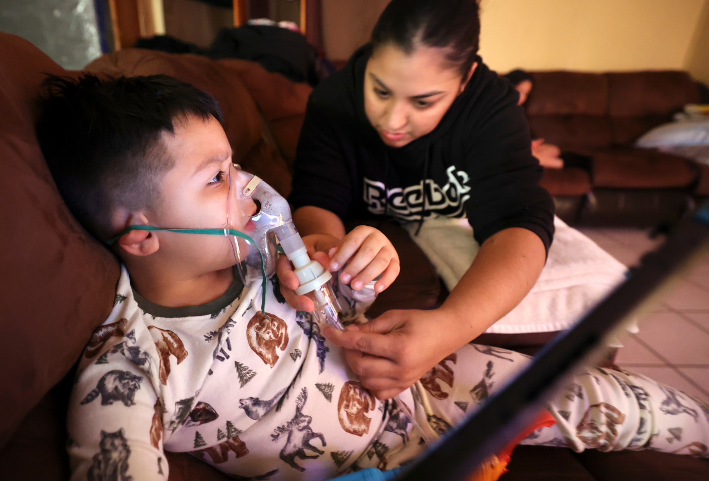 Rosa Mandujano reattaches part of her son Ruben Mandujano’s nebulizer after he pulled it off prematurely hoping he was done, at their home near the Salton Sea and Mecca, California, on Thursday, Dec. 14, 2023. Ruben, 5, has asthma and is autistic. He doesn’t like the nebulizer, which administers albuterol, as it often makes him throw up. Kristin Murphy, Deseret News.